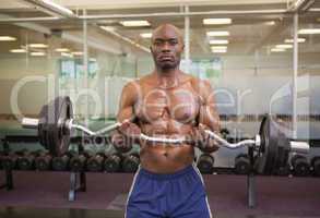 Muscular man lifting barbell in gym