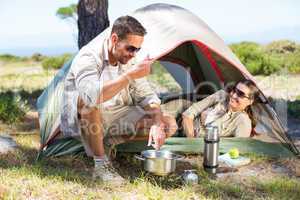 Outdoorsy couple cooking on camping stove outside tent