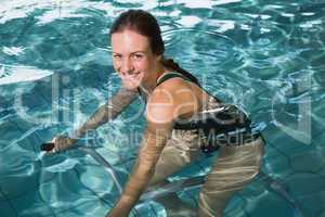 Fit brunette using underwater exercise bike