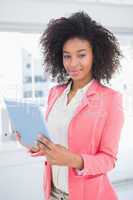 Casual businesswoman smiling at camera holding tablet pc