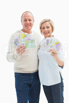 Happy mature couple smiling at camera showing money