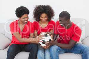 Football fans sitting on couch holding ball