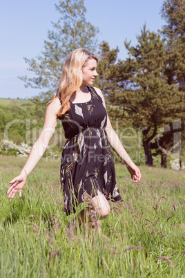 Pretty blonde in sundress walking through field