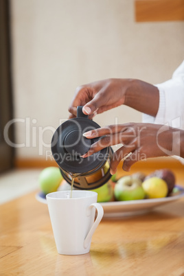 Woman in bathrobe pouring coffee