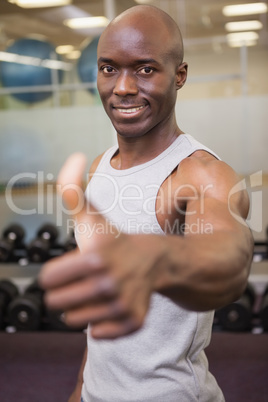 Muscular man giving thumbs up in gym