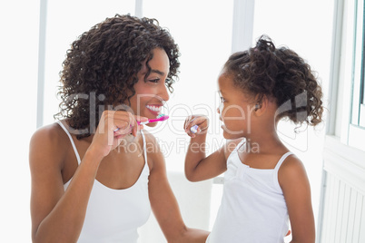 Pretty mother with her daughter brushing their teeth