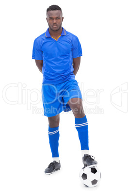 Football player in blue standing with ball