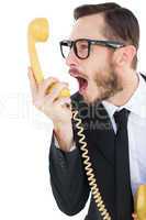 Geeky businessman shouting at telephone