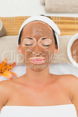 Smiling brunette getting a mud treatment facial
