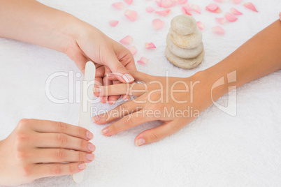 Beautician filing female clients nails at spa beauty salon