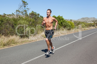 Shirtless man jogging on open road