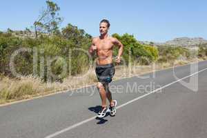 Shirtless man jogging on open road