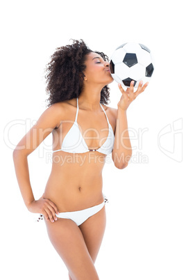 Smiling fit girl in white bikini kissing football