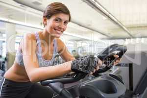 Fit smiling brunette working out on the exercise bike