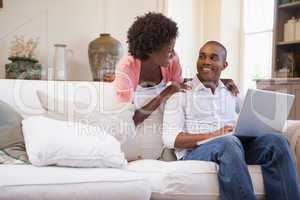 Happy couple relaxing together on the couch using laptop