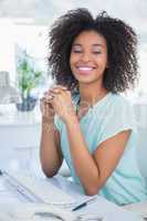 Casual businesswoman smiling at camera at her desk