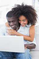 Attractive couple using laptop together on sofa