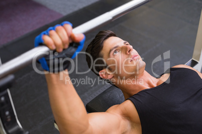 Determined muscular man lifting barbell in gym