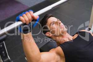 Determined muscular man lifting barbell in gym