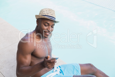 Handsome shirtless man texting on phone poolside