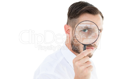 Geeky businessman looking through magnifying glass