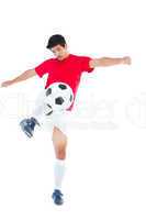 Football player in red kicking ball