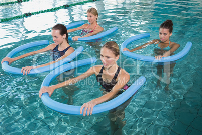 Fitness class doing aqua aerobics with foam rollers