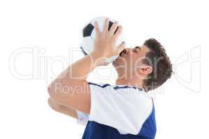 Football player in blue kissing the ball