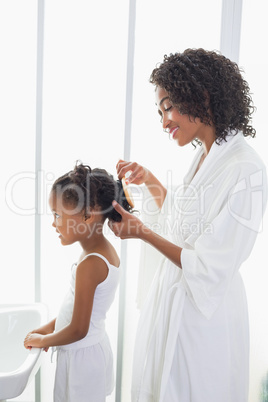 Pretty mother brushing her daughters hair