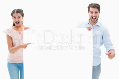 Attractive young couple smiling at camera holding poster