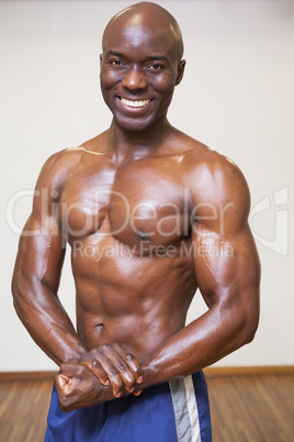 Smiling shirtless muscular man posing in gym