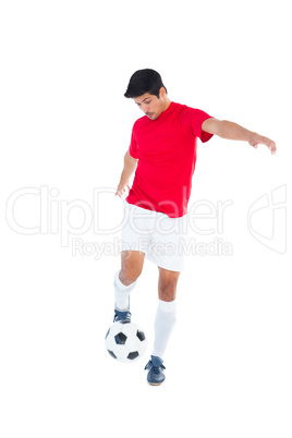 Football player in red kicking ball