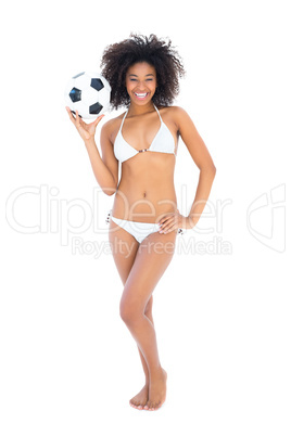 Smiling fit girl in white bikini holding football