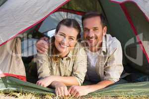 Outdoorsy couple smiling at camera from inside their tent