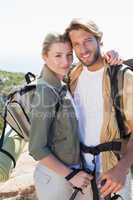 Attractive hiking couple smiling at camera on mountain trail
