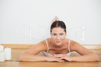 Smiling brunette lying on floor looking at camera