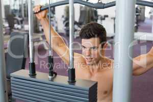 Muscular man exercising on a lat machine in gym