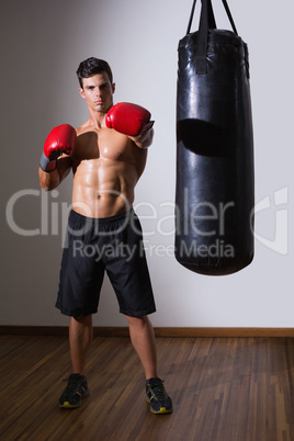 Muscular boxer with punching bag in gym