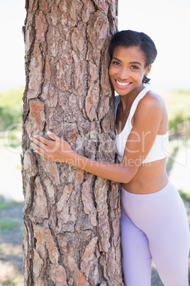 Fit woman hugging a tree smiling at camera Fit woman hugging a tree smiling at camera