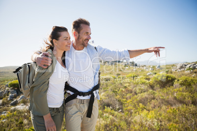 Hiking couple pointing and smiling on country terrain