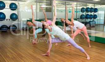 Yoga class in extended triangle pose in fitness studio