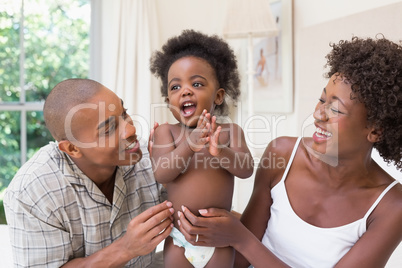 Happy couple on bed with baby daughter