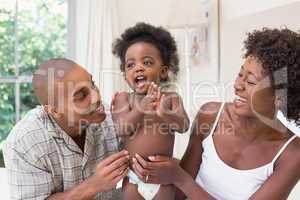 Happy couple on bed with baby daughter