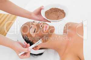 Smiling brunette getting a mud treatment facial