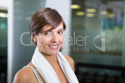 Fit brunette smiling at camera with towel around shoulders