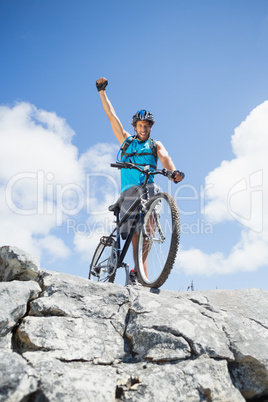 Fit man cycling on rocky terrain and cheering