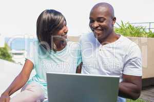 Happy couple sitting in garden using laptop together