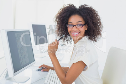 Pretty casual businesswoman smiling at camera at desk