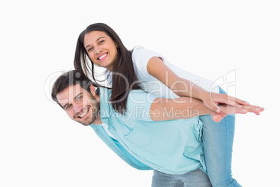 Happy casual man giving pretty girlfriend piggy back