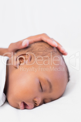 Adorable baby boy sleeping with fathers hand on head